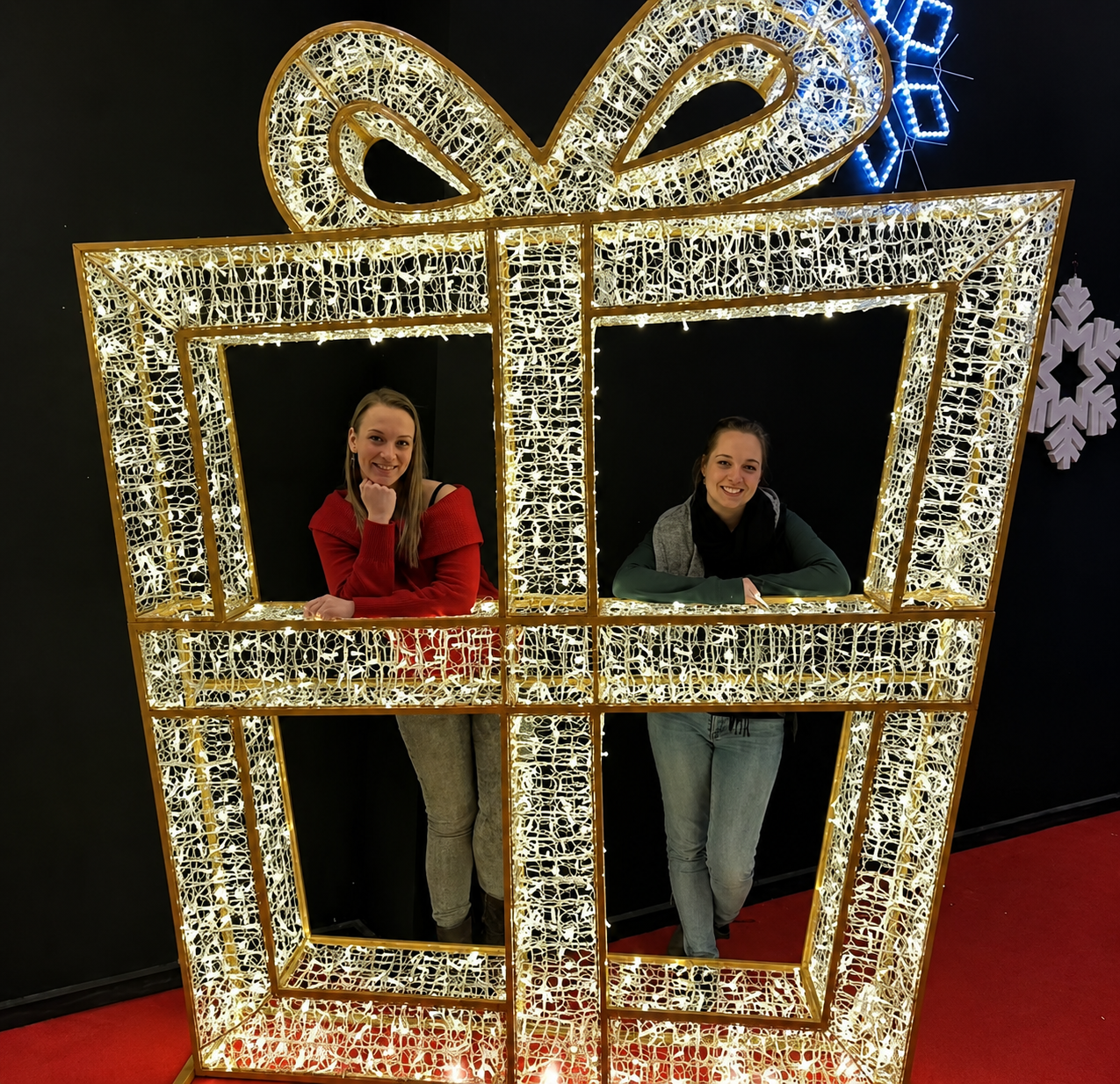 Two guests posing inside an illuminated giant gift box light display