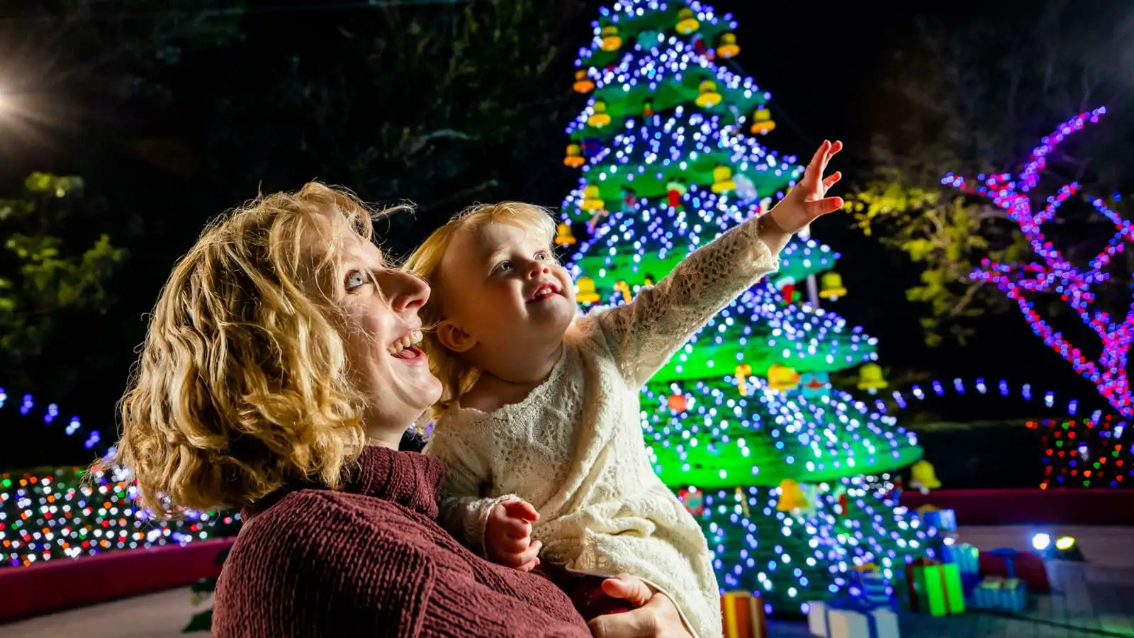 Mother and daughter in awe of a glowing Christmas tree display